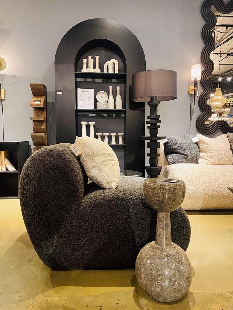 Curved sofas and accent tables. A cursed top bookcase displaying white marble curved accessories